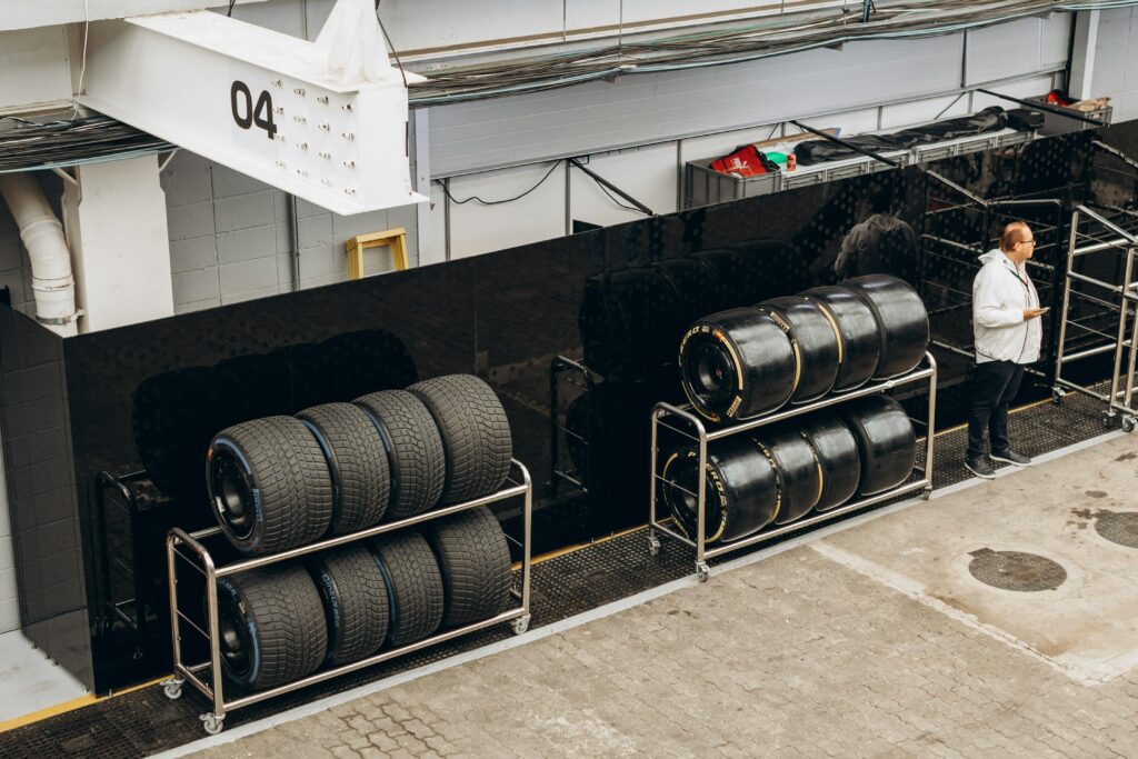 High-performance racing tires stacked in a pit garage with a technician onsite.