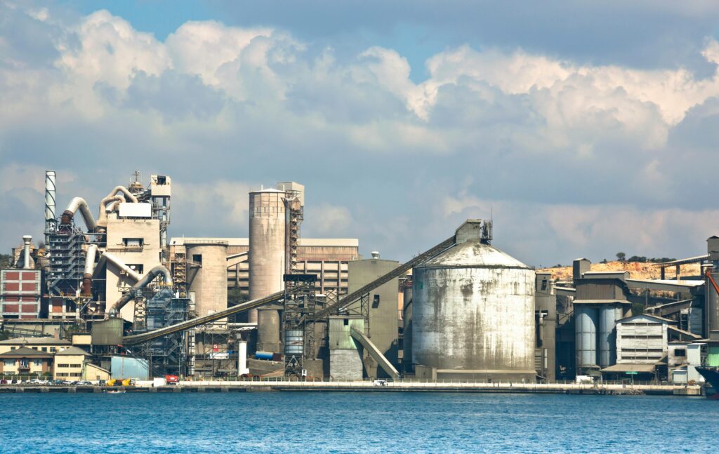 A sprawling industrial factory complex by the sea, captured on an overcast day, showcasing diverse structures.