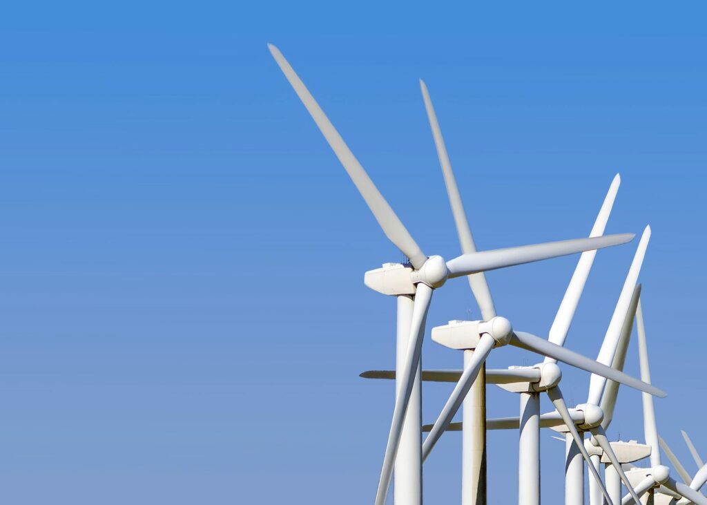 Wind turbines generating clean energy stand tall against a clear blue sky, highlighting sustainable technology.