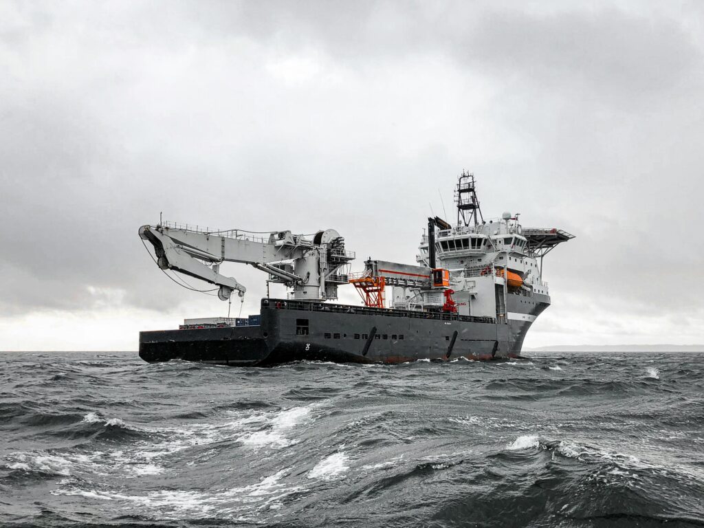 A large industrial ship cruising through a stormy sea under a cloudy sky, showcasing marine engineering and transportation.